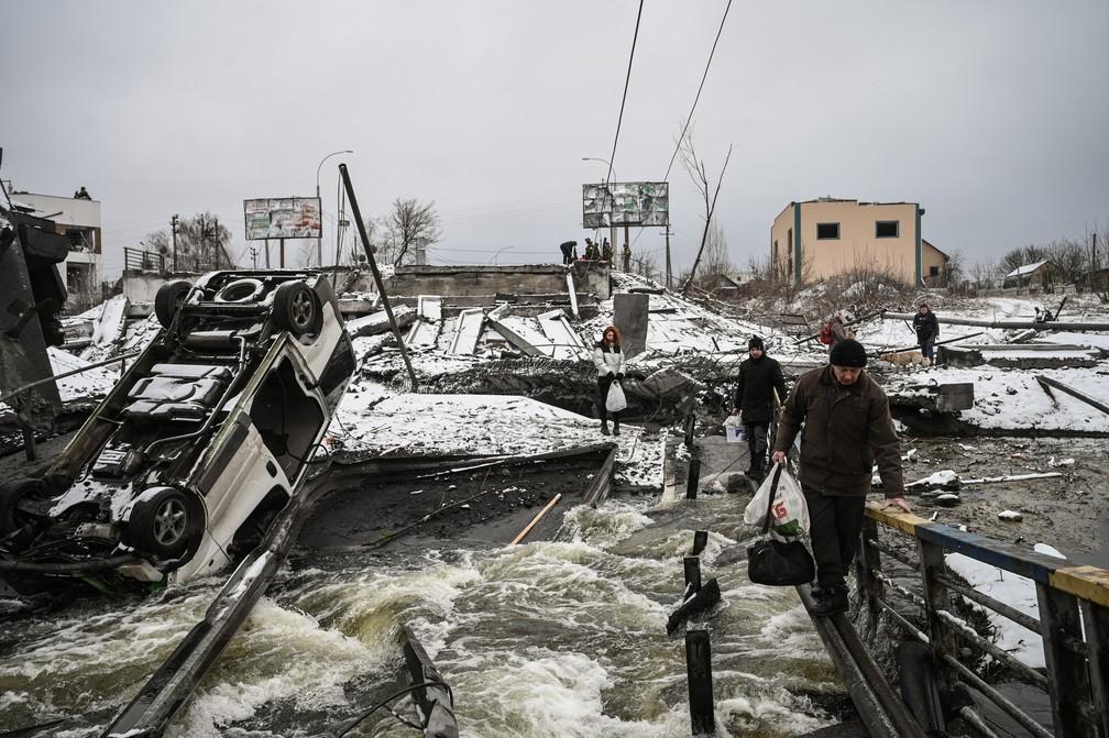 1 de maro - Civis cruzam uma ponte destruda por bombardeio na parte norte de Kiev capital da Ucrnia Foto Aris MessinisAFP