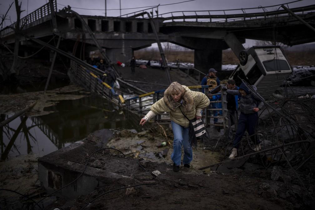 0203 - Uma mulher corre enquanto foge com sua famlia por uma ponte destruda nos arredores de Kiev na Ucrnia nesta quarta-feira 02 Foto Emilio MorenattiAP