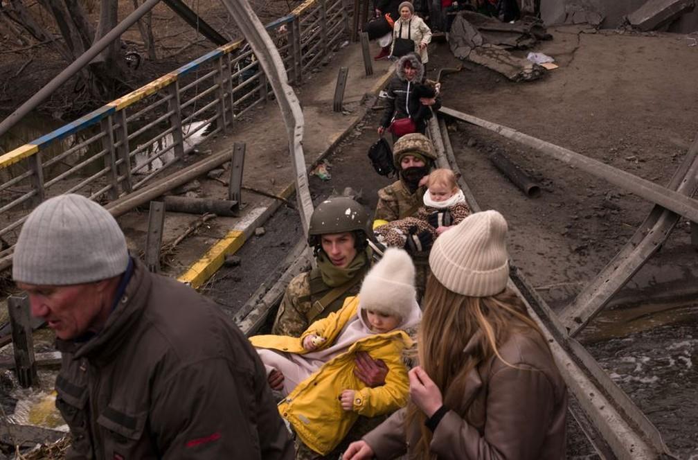Soldado carrega criana em travessia de ponte fugindo de Irpin Foto Gabriel Chaimg1
